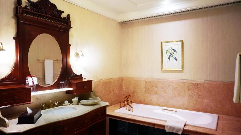Hotel Majapahit Surabaya MGallery – hôtel à Surabaya, Indonésie – une salle de bain avec un lavabo et un grand miroir à l'Hotel Majapahit Surabaya MGallery à Surabaya