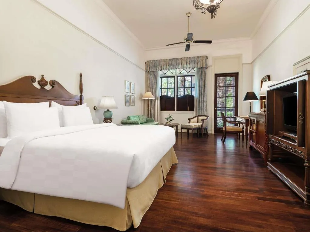 Hotel Majapahit Surabaya MGallery – hôtel à Surabaya, Indonésie – une chambre avec un grand lit blanc et une télévision à l'Hotel Majapahit Surabaya MGallery à Surabaya
