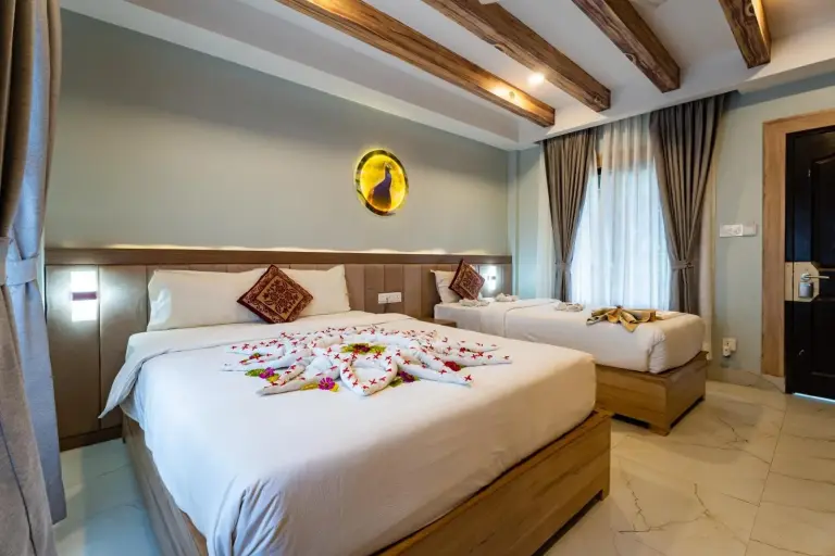 Chambre twin à Hotel Seven Limited à Sauraha avec décoration moderne et arrangement floral sur le lit.