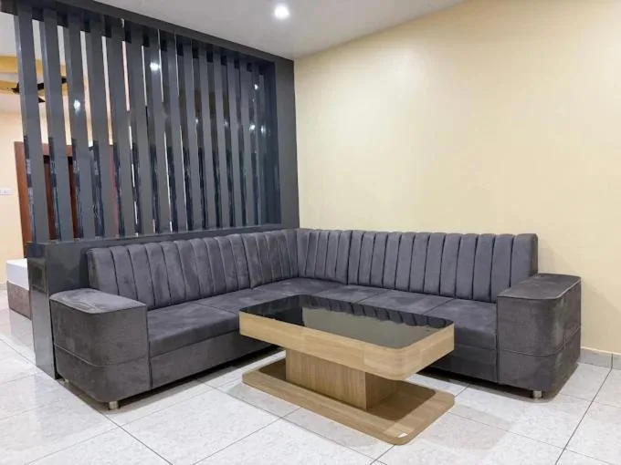 Moderner Sitzbereich mit Sofa im Hotel Swagat Inn in Dhangadhi mit grauem Ecksofa und Couchtisch mit Glasplatte.