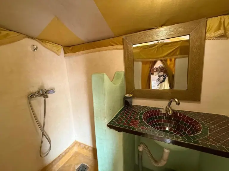 Espace douche et lavabo au Houda Luxury Camp Merzouga à Merzouga avec meuble vasque en mosaïque et salle de bains privative sous tente.