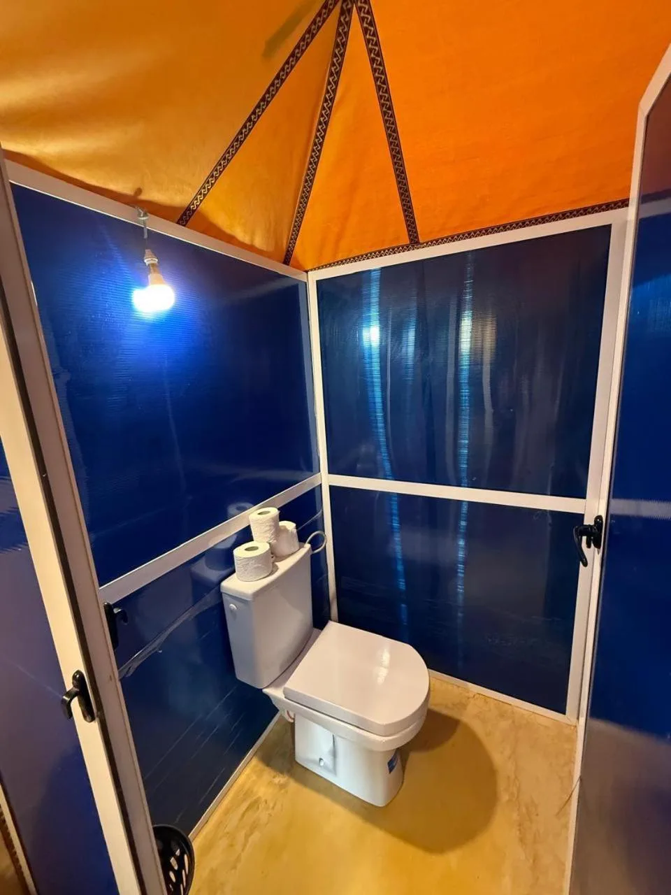 Toilettes privatives au Houda Luxury Camp Merzouga à Merzouga avec panneaux muraux bleus et porte-papier toilette.