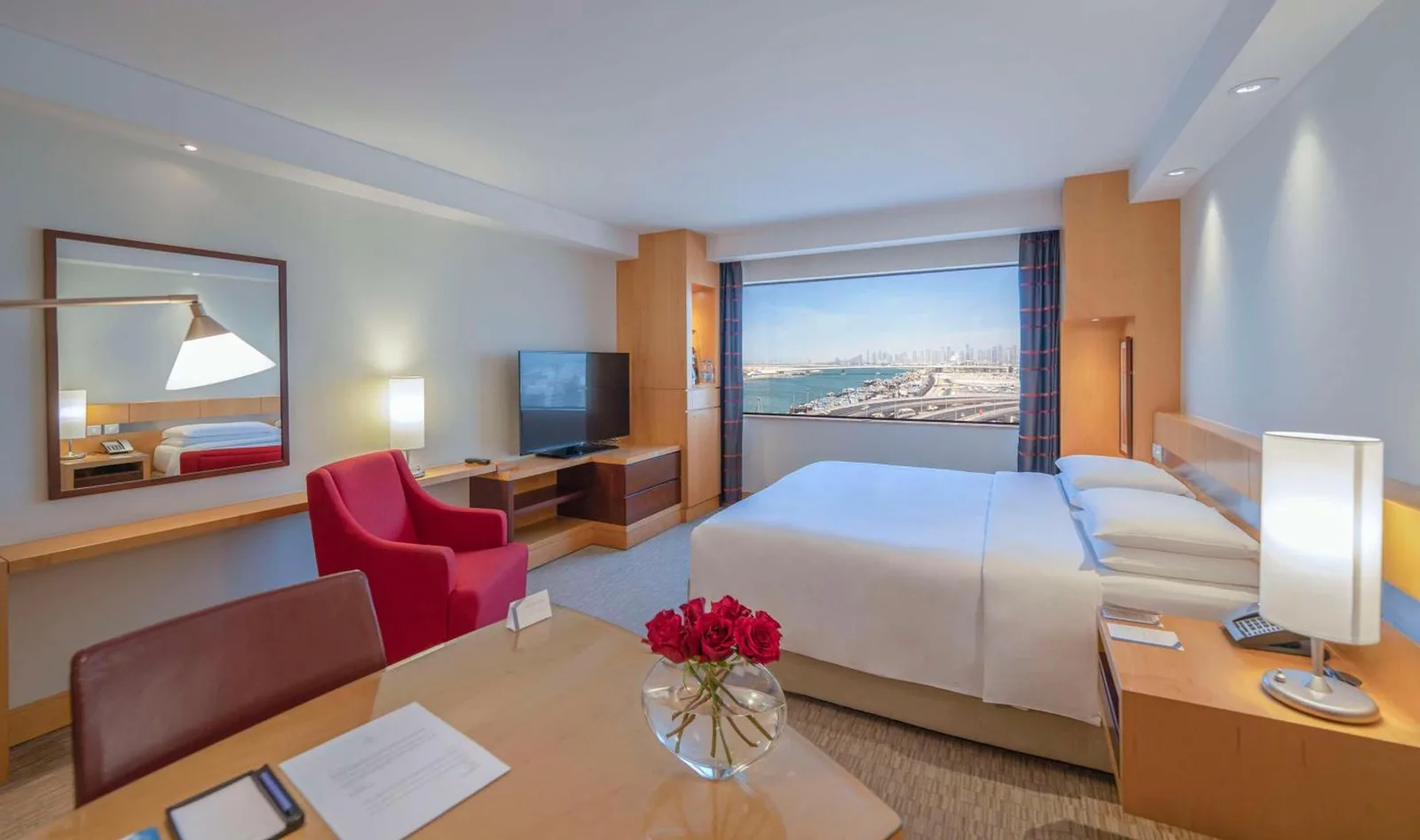 Gästezimmer im Hyatt Regency Dubai - Corniche mit Bett, Sitzbereich und Blick auf den Hafen