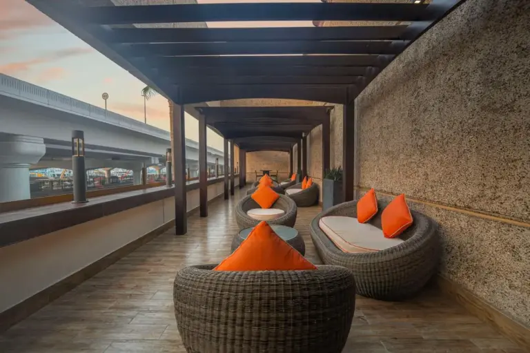 Sitzbereich auf der Außenterrasse im Hyatt Regency Dubai - Corniche mit Rattanstühlen und Sonnenuntergangsblick