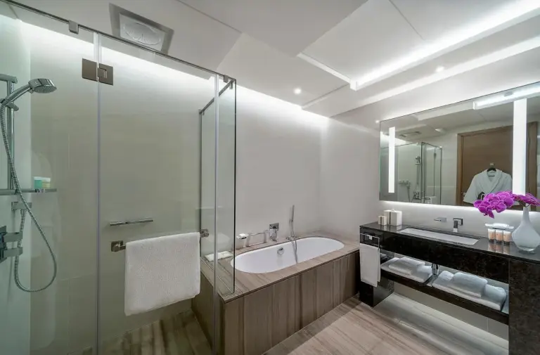 Modern bathroom at Hyatt Regency Dubai Creek Heights in Dubai with bathtub, glass shower, and double vanity