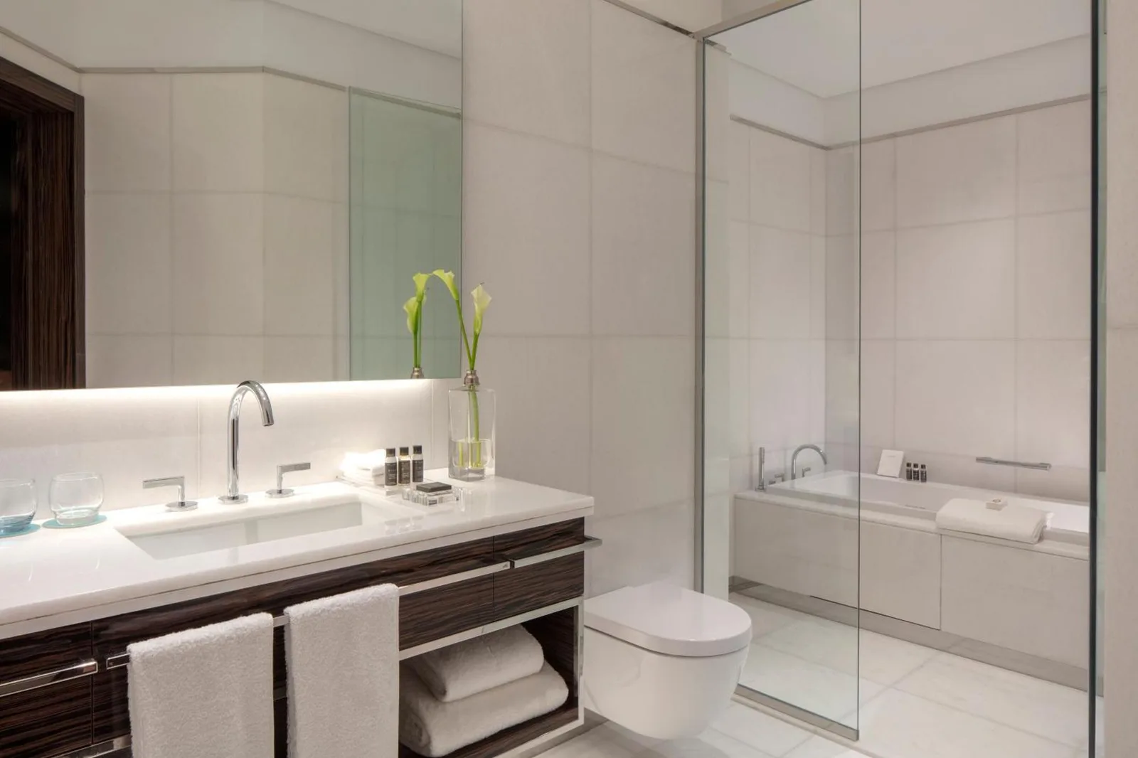 Baño contemporáneo en Hyde Hotel Dubai en Dubai con tocador de doble lavabo, bañera y mampara de cristal.