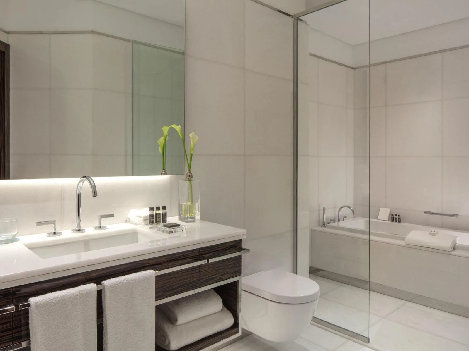 Baño moderno en Hyde Hotel Dubai en Dubai con tocador doble, espejo y zona de bañera cerrada con cristal.