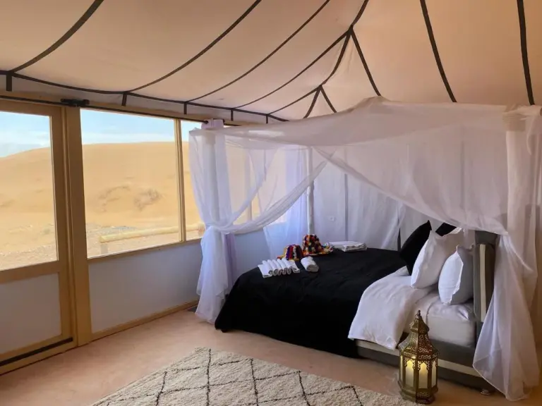 Interior of ITRAN ROYAL CAMP tent featuring a luxurious double bed and desert views.