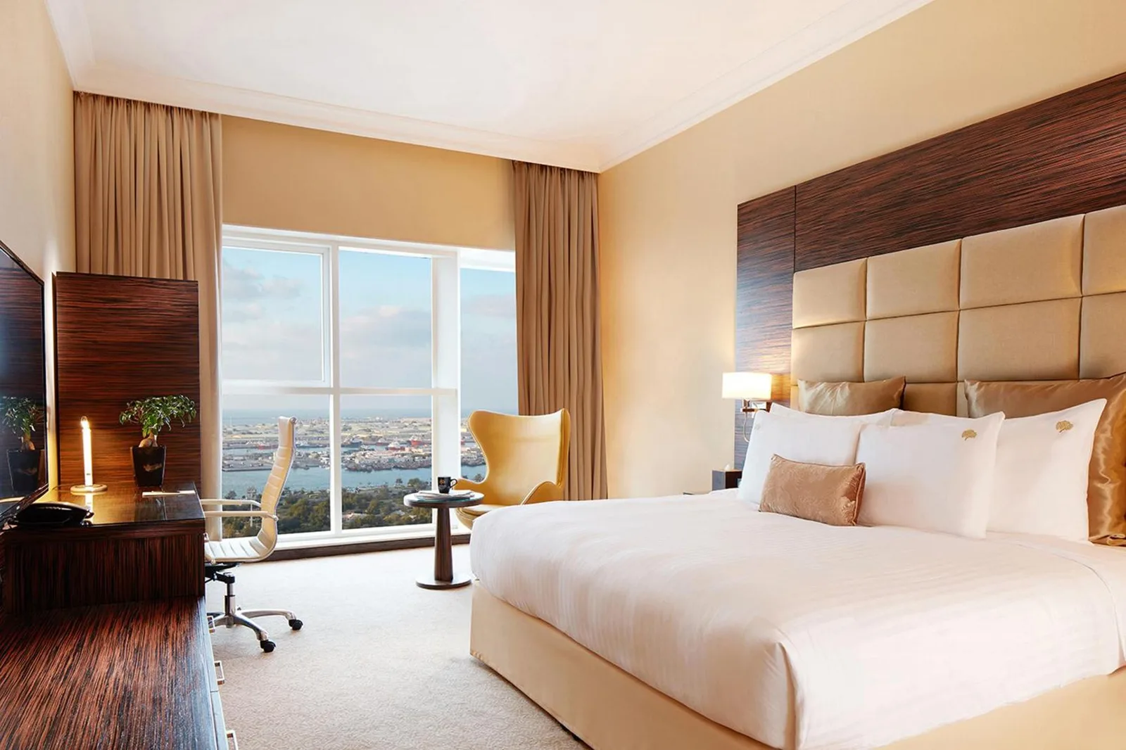 Twin room at Jannah Burj Al Sarab Abu Dhabi with two beds, desk, and window view.