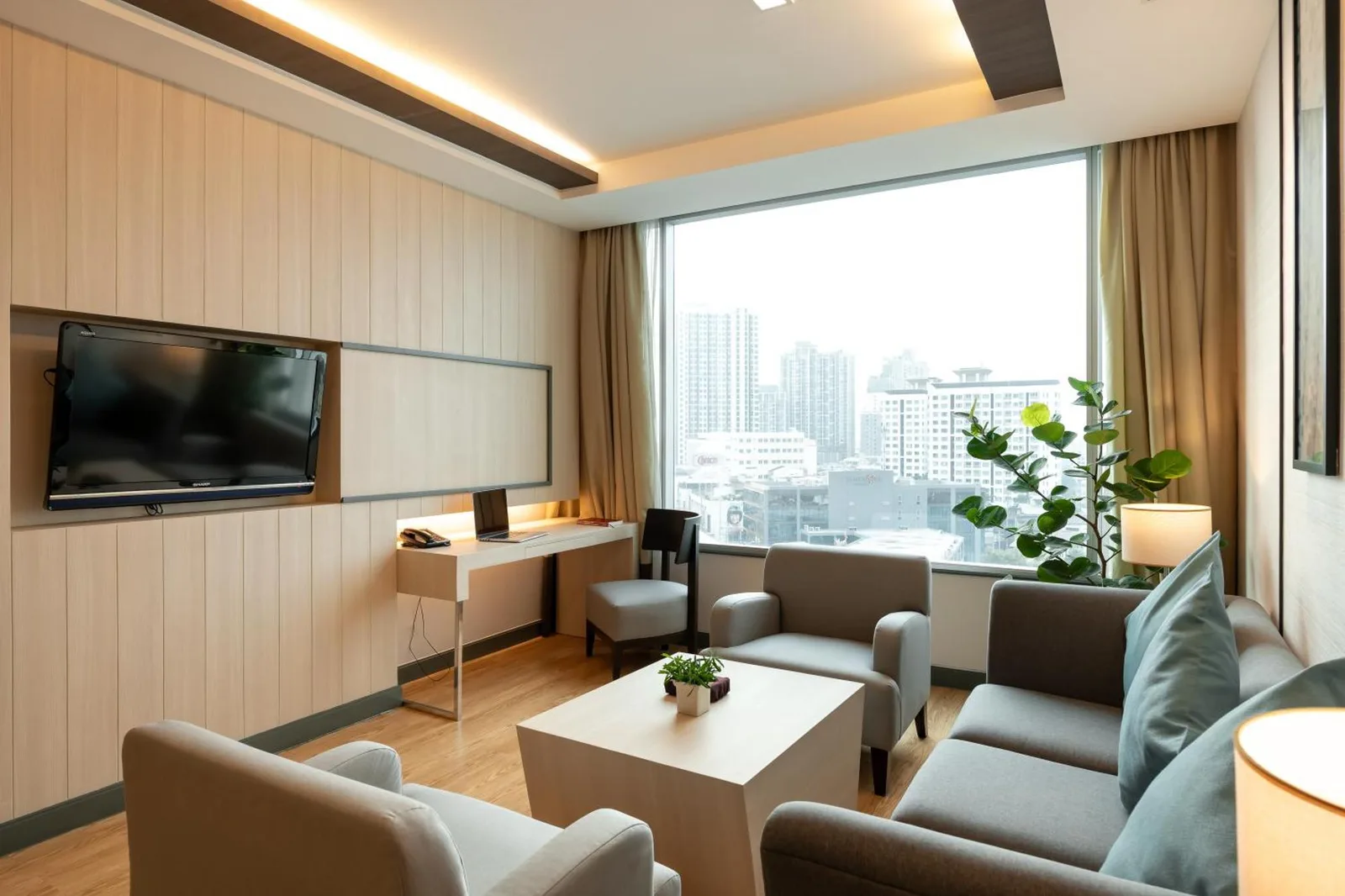 Salon de suite au Jasmine Resort Hotel Bangkok BTS Phrakhanong avec canapé, fauteuils et vue sur la ville