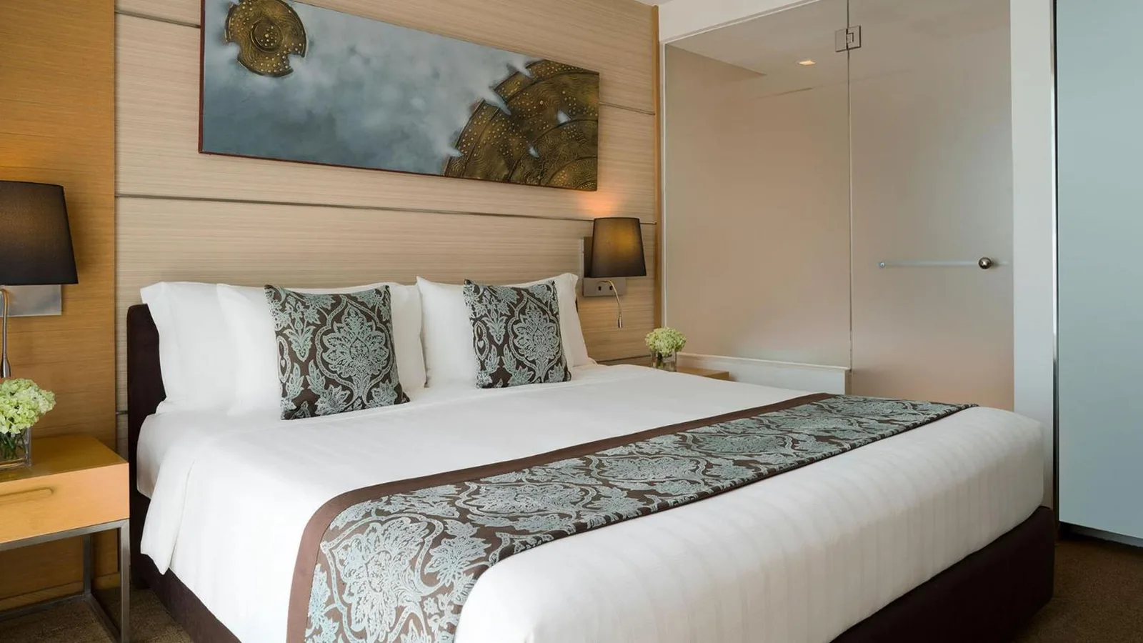 A stylish deluxe bedroom at JC Kevin Sathorn Bangkok Hotel with a king bed and modern decor.