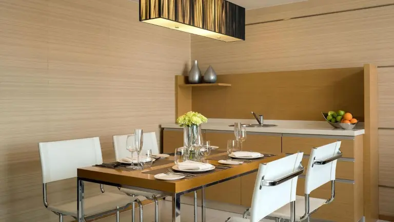 Dining area inside a suite at JC Kevin Sathorn Bangkok Hotel with a set table and kitchenette.