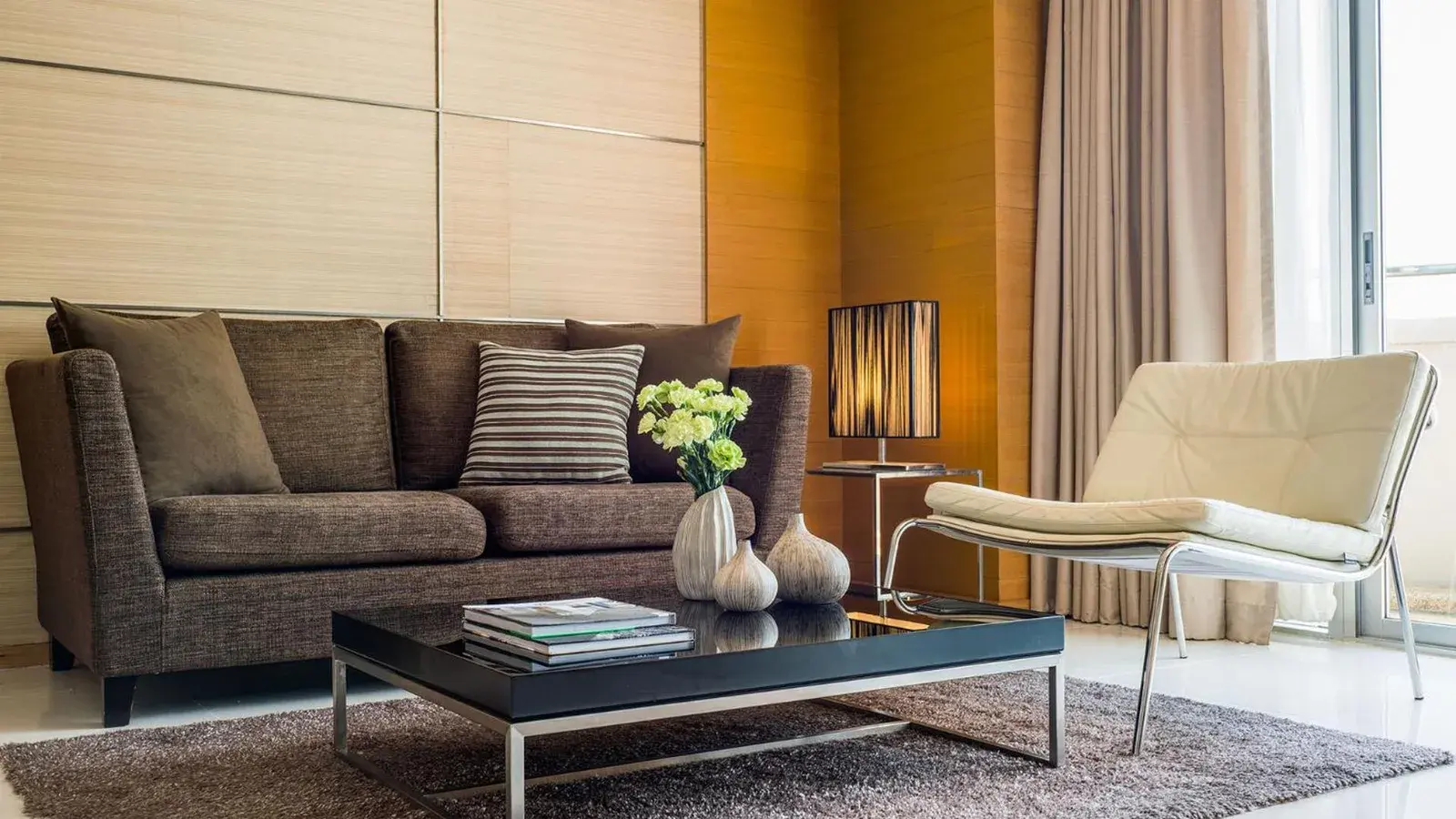 Spacious living room at JC Kevin Sathorn Bangkok Hotel with sofa, chair, and coffee table.