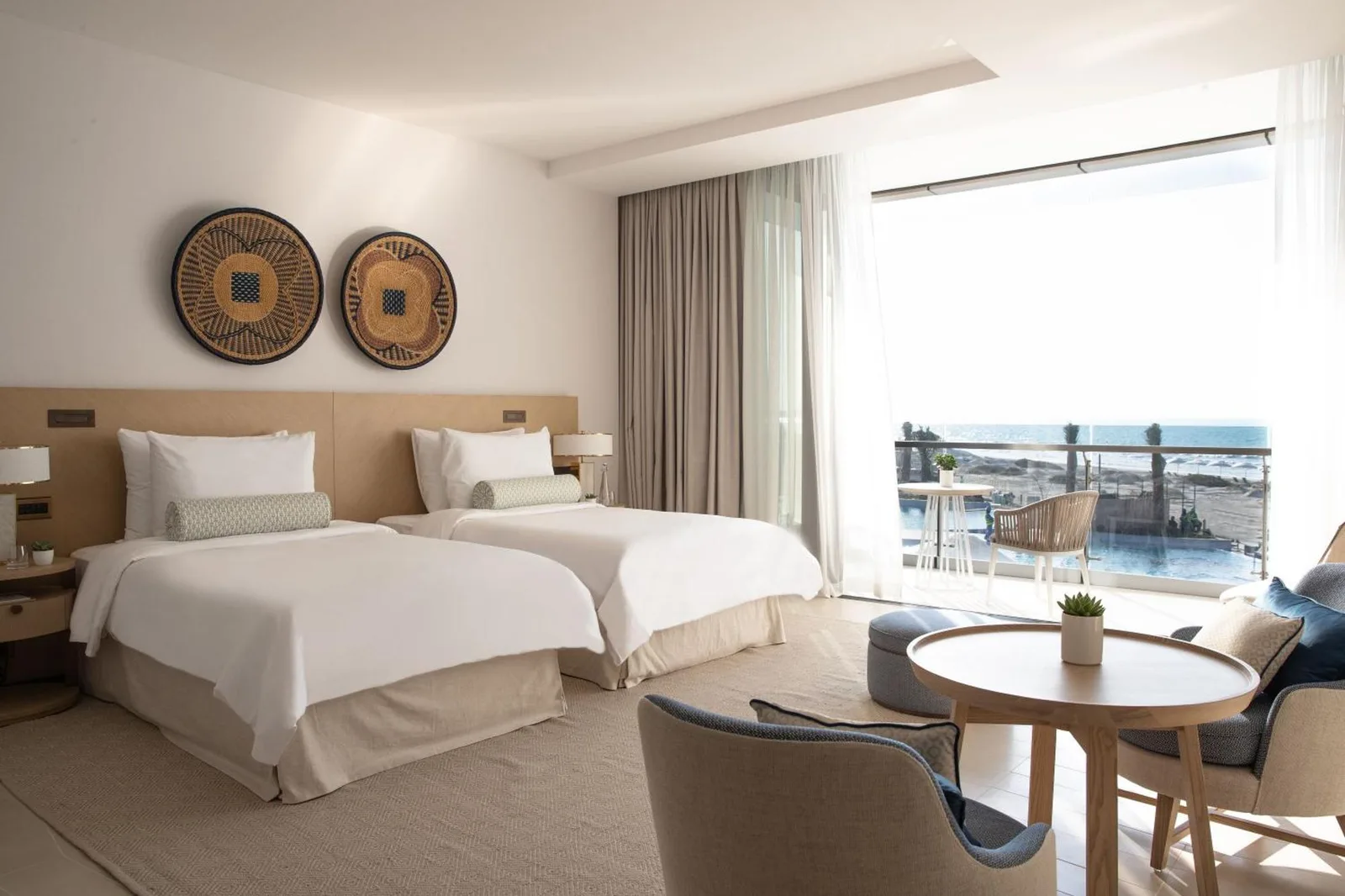 Jumeirah Saadiyat Island Abu Dhabi – Hotel in Abu Dhabi, Vereinigte Arabische Emirate – ein Hotelzimmer mit zwei Betten und einem Tisch im Jumeirah Saadiyat Island Abu Dhabi in Abu Dhabi