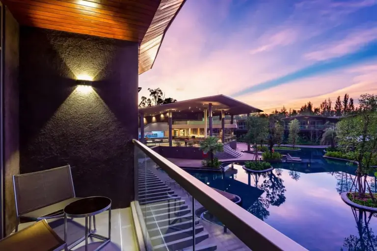 Balcony at Kalima Resort and Villas Khao Lak overlooking the resort pool and sunset sky in Khao Lak.