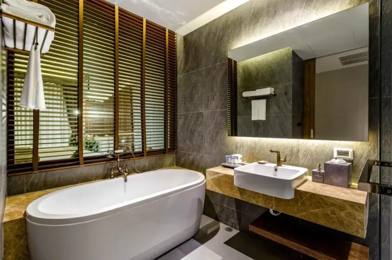 Bathroom at Kalima Resort and Villas Khao Lak with bathtub, sink, and elegant stone decor in Khao Lak.