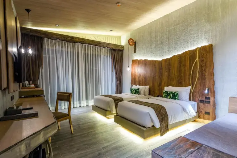 Family room at Kalima Resort and Villas Khao Lak with two beds, soft lighting, and a modern resort interior.