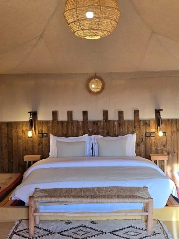 Interior acogedor de una tienda en Kalimba Luxury Desert Camp con una cama y características de madera