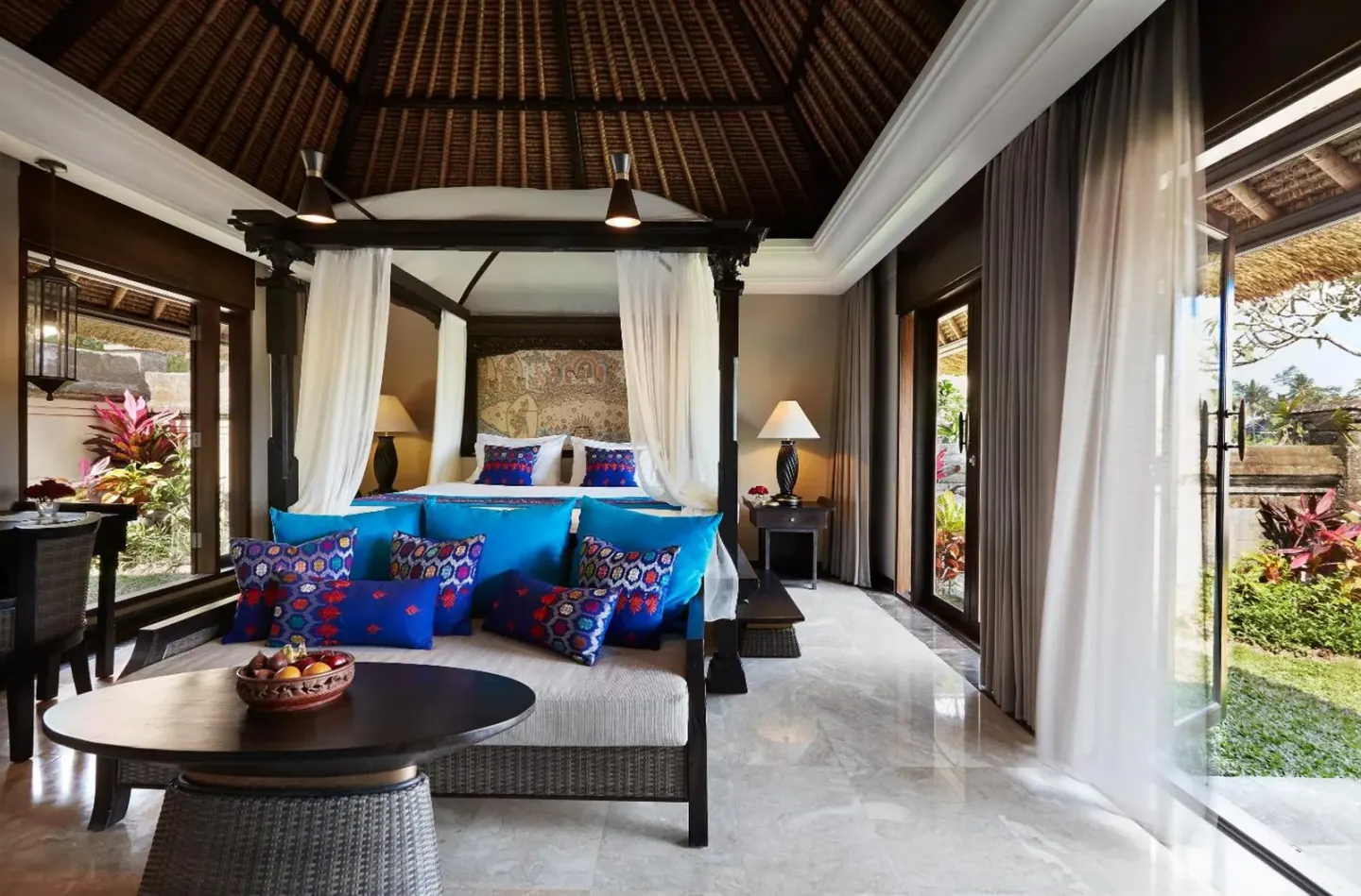 a living room with a blue couch and a bed at Kamandalu Ubud in Ubud