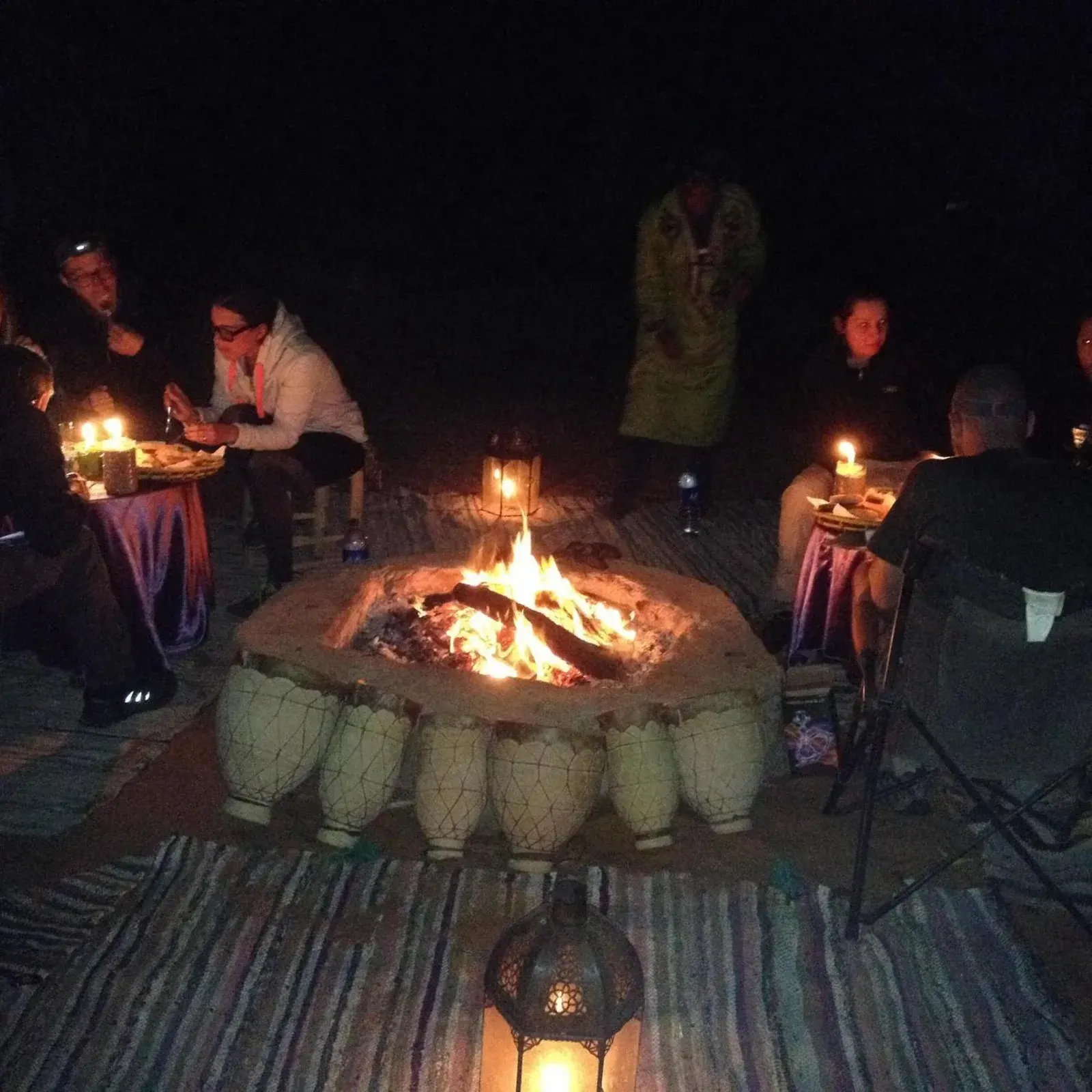 Clients dînant autour d’un feu de camp au Kasbah Planet Sahara hotel à Merzouga la nuit
