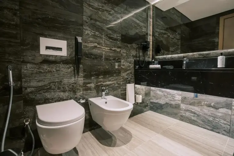 Modernes Badezimmer im Khalidia Palace Hotel Dubai mit dunklen Steinoberflächen, Waschbecken, Toilette und Bidet