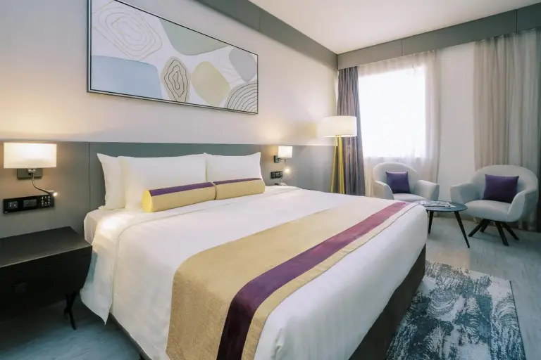 Stilvolles Gästezimmer im Khalidia Palace Hotel Dubai mit Kingsize-Bett, Sitzbereich und viel Tageslicht