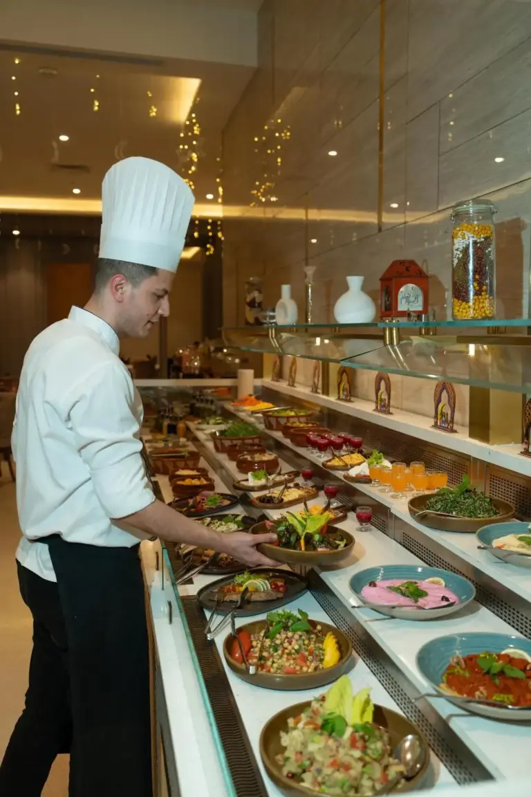 Koch richtet im Restaurant des Khalidia Palace Hotel Dubai Buffetgerichte an, mit einer Auswahl an angerichteten Speisen