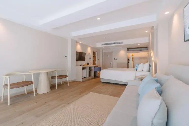 Suite living area at Khaolak Emerald Beach Resort and Spa in Khao Lak with a sofa, dining table, and bedroom space.
