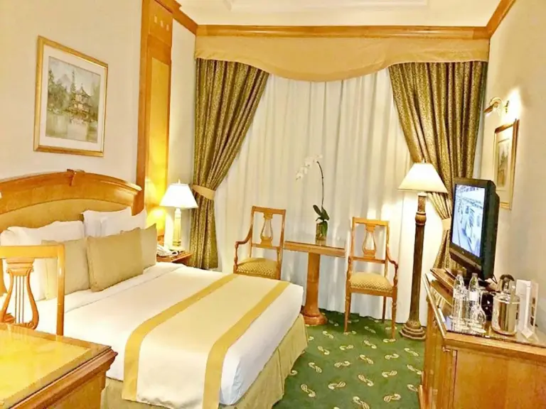 Knight Castle Hotel - Formerly known as Carlton Palace Hotel Dubai Gästezimmer mit Kingsize-Bett, Vorhängen und Fernseher.
