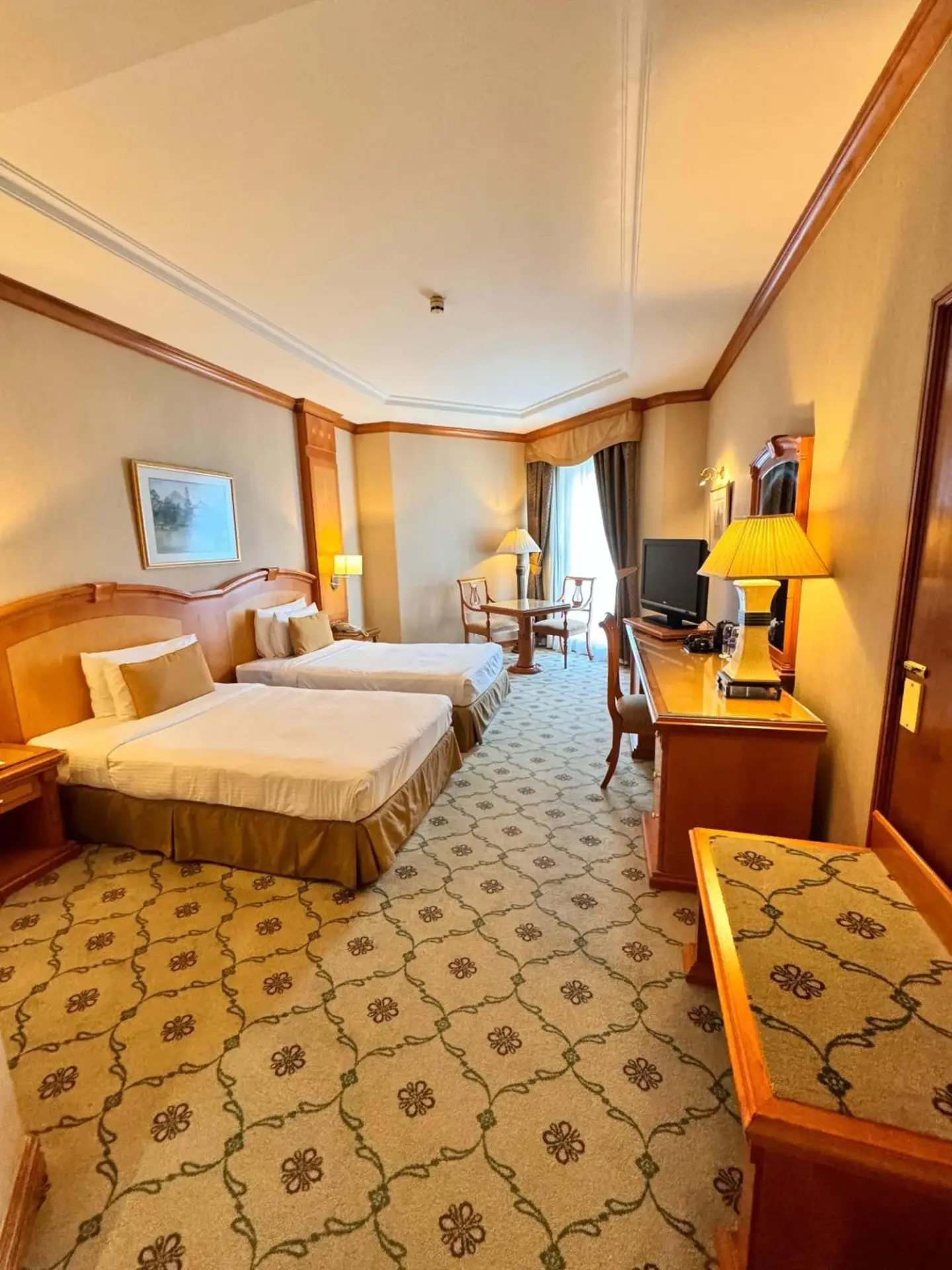 Knight Castle Hotel - Formerly known as Carlton Palace Hotel Dubai Zweibettzimmer mit zwei Betten, Schreibtisch und warmem Licht.