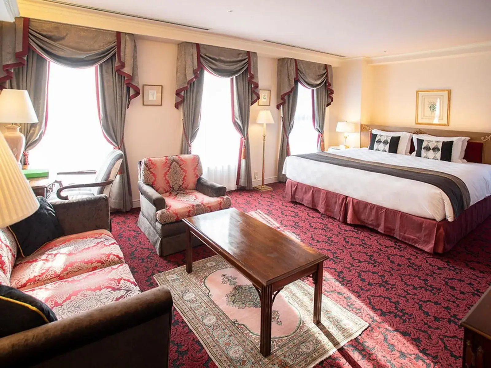 Geräumiger Wohnbereich mit Bett und Sitzgelegenheiten im Kobe Kitano Hotel