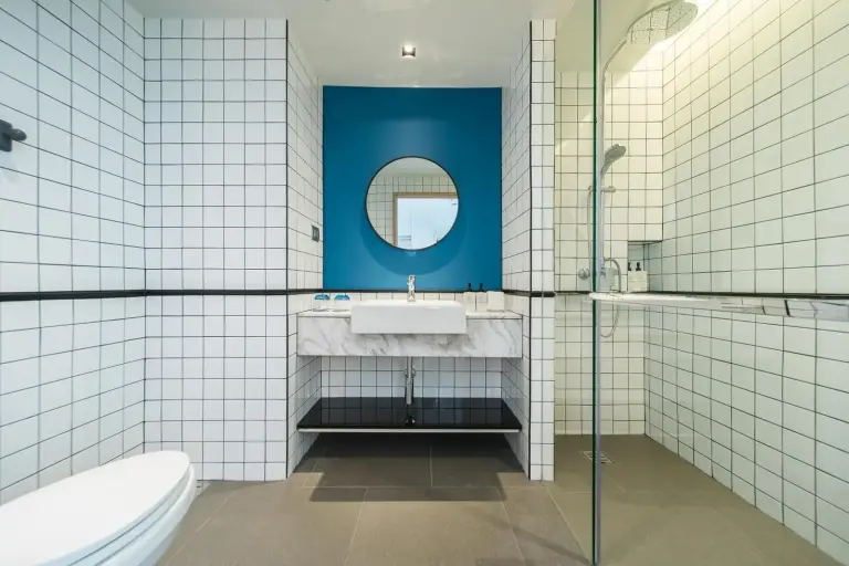 Modern bathroom vanity at Kram Pattaya hotel in Pattaya with blue accent wall and glass shower