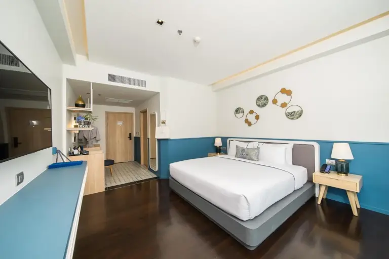 King bedroom at Kram Pattaya hotel in Pattaya with large bed, bedside lamps, and entrance area