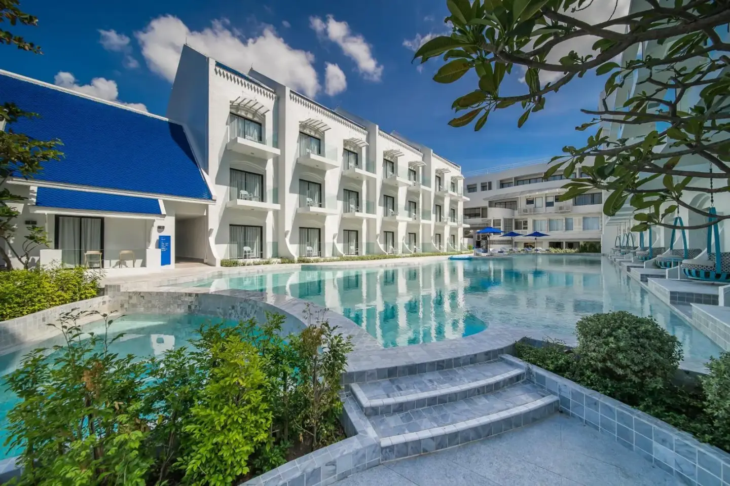 Exterior pool area at Kram Pattaya hotel in Pattaya with modern white buildings and a large swimming pool