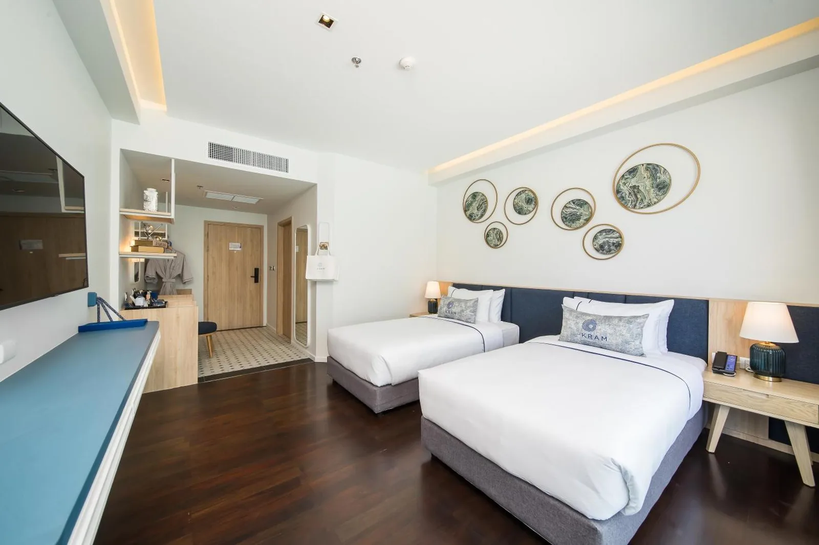Spacious twin room at Kram Pattaya hotel in Pattaya with two beds, work area, and entrance view