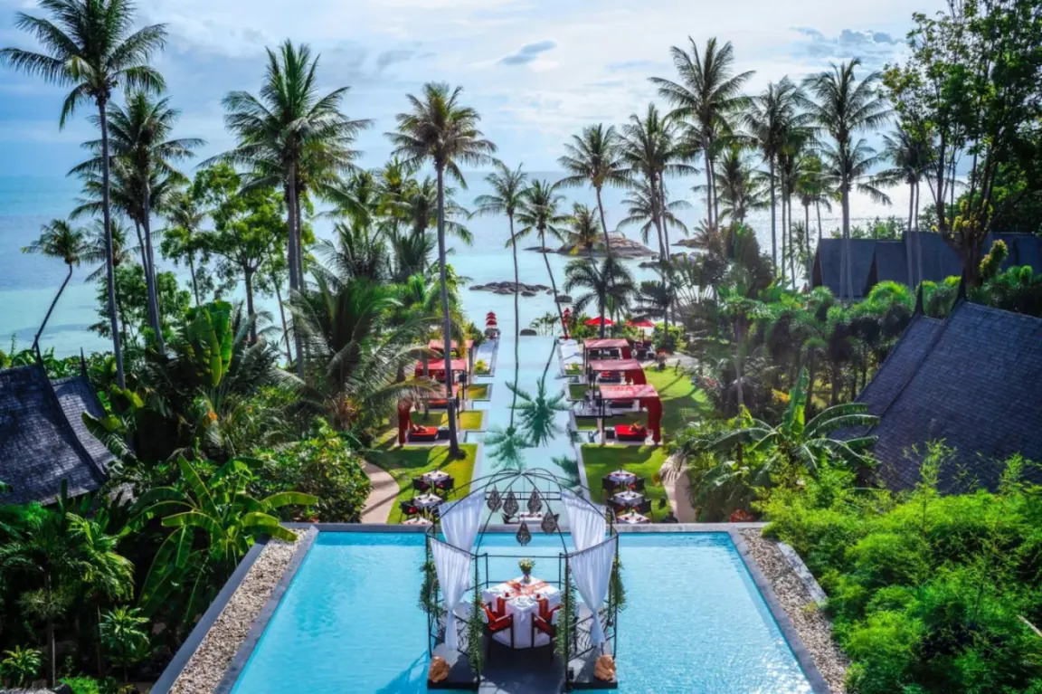 Stunning view of Kupu Kupu Phangan Beach Villas & Spa's infinity pool surrounded by palm trees