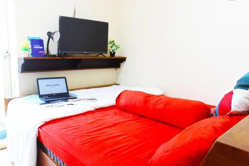Bedroom setup at Lagura Residence in Jakarta with a desk and a laptop