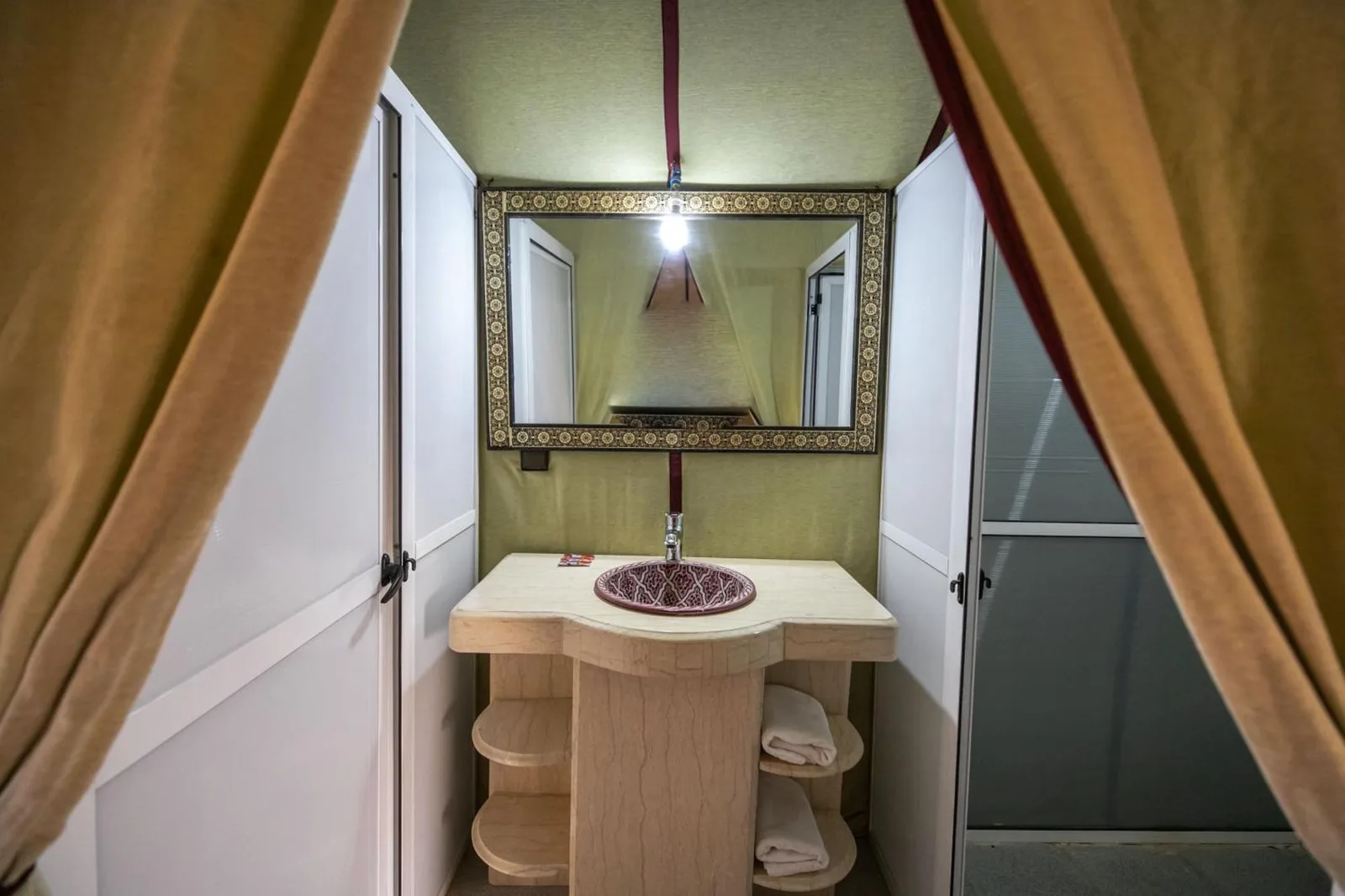 Stilvolle Badezimmerkonsole im Lana Camp Merzouga in Merzouga mit Spiegel, Waschbecken und Handtüchern.