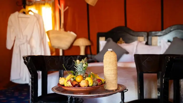 Gemütliches Zelt-Schlafzimmer im Lana Camp Merzouga in Merzouga mit Bett, Bademantel und warmer Einrichtung.