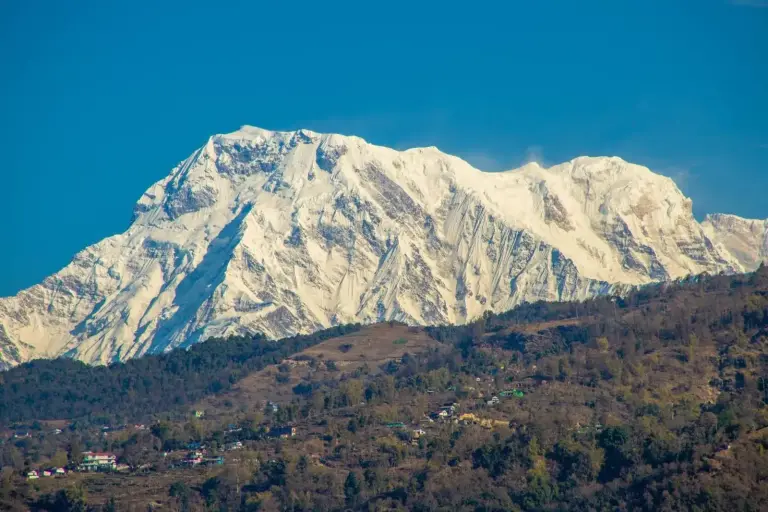 Vista de montañas nevadas desde Landmark Pokhara en Pokhara con cielo azul despejado y estribaciones boscosas.