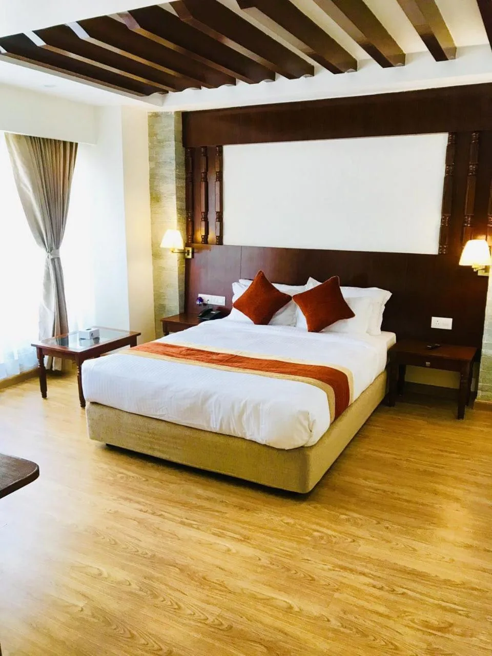 Habitación de huéspedes con cama queen en Landmark Pokhara en Pokhara, con cálidos detalles de madera y decoración moderna.