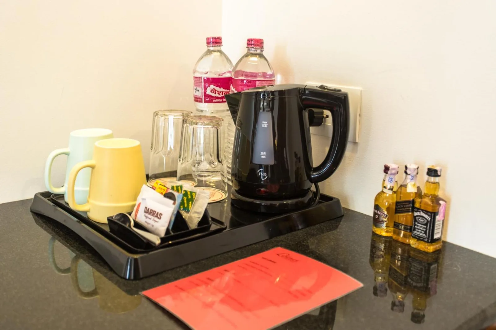 Montaje de té y café en la habitación de Landmark Pokhara en Pokhara con hervidor, tazas, botellas de agua y aperitivos.