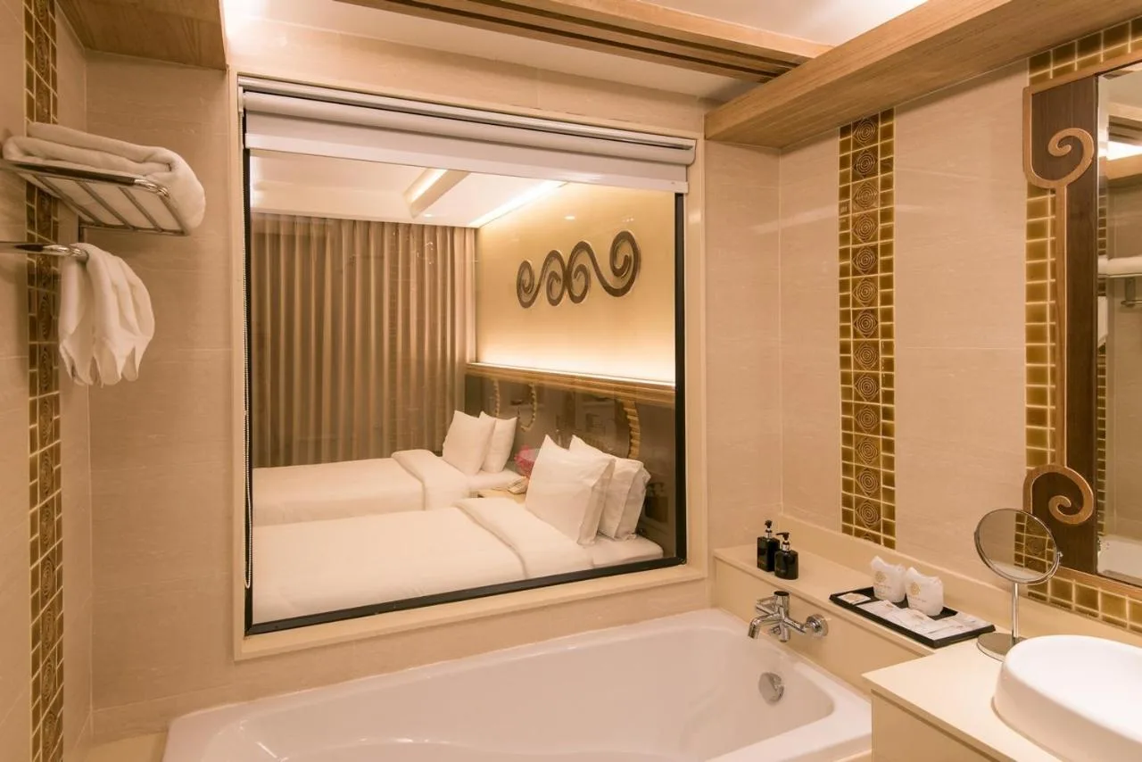 Baño de Le Bali Resort Pattaya con bañera, lavabo, espejo y reflejo del dormitorio