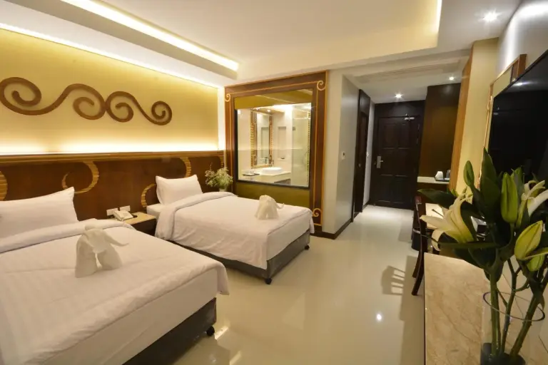 Habitación familiar de Le Bali Resort Pattaya con dos camas, ventana con vistas al baño y decoración moderna