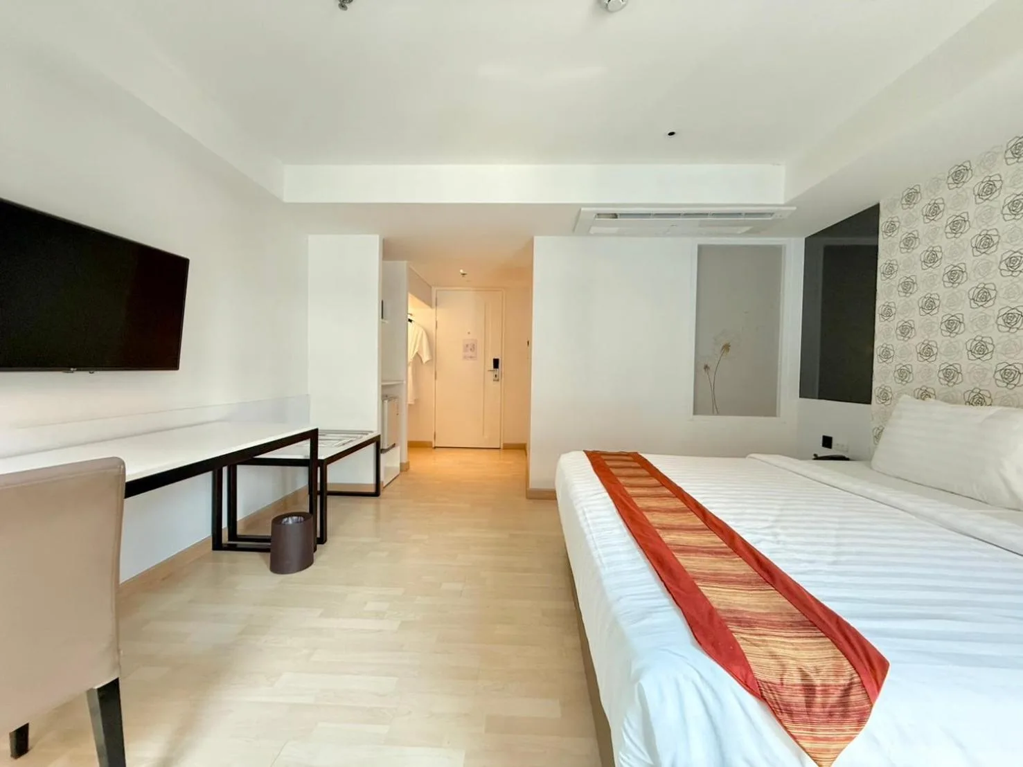 Frontansicht eines Kingsize-Schlafzimmers im Le D'Tel Bangkok mit gemusterter Wand, Nachttischen und orangefarbenen Akzentkissen.