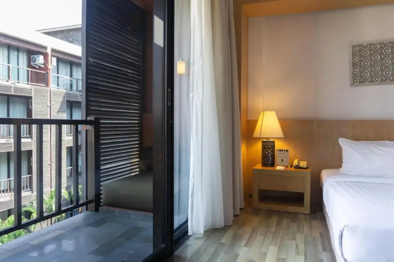 Balcony bedroom at Le Grande Bali in Uluwatu featuring a bed, bedside lamp, and private balcony access.
