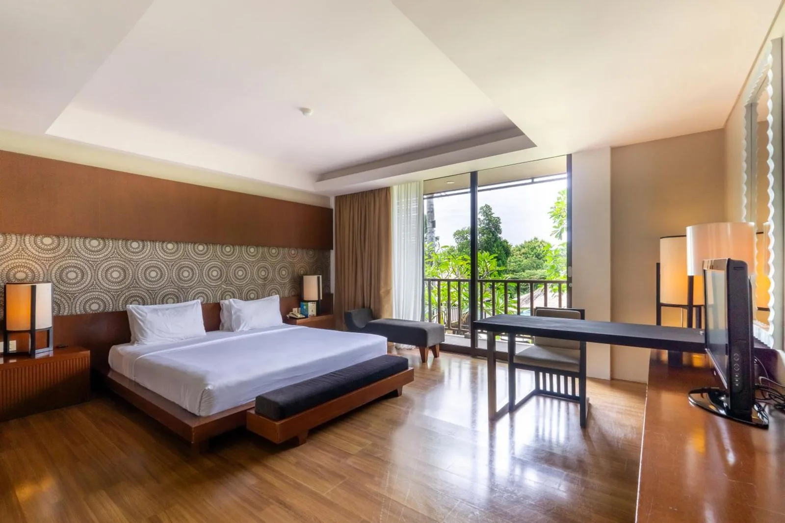 Spacious king bedroom at Le Grande Bali in Uluwatu with a balcony, lounge chair, and modern decor.