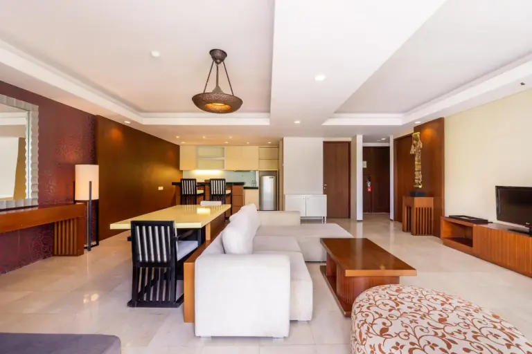 Living room at Le Grande Bali in Uluwatu with sofa seating, dining table, kitchen area, and TV.
