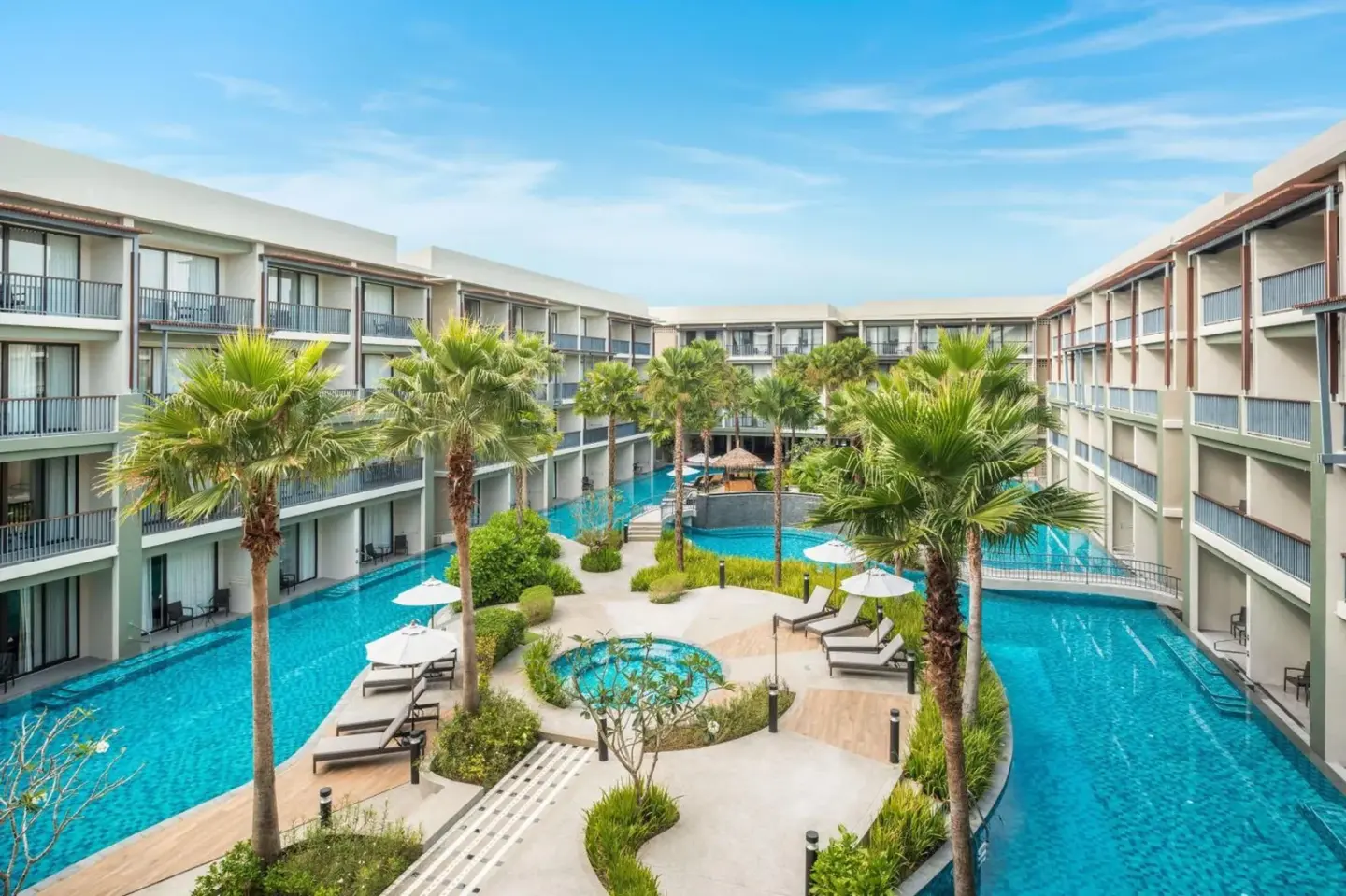Central courtyard pool area at Le Meridien Khao Lak Resort & Spa with palm trees and sun loungers.