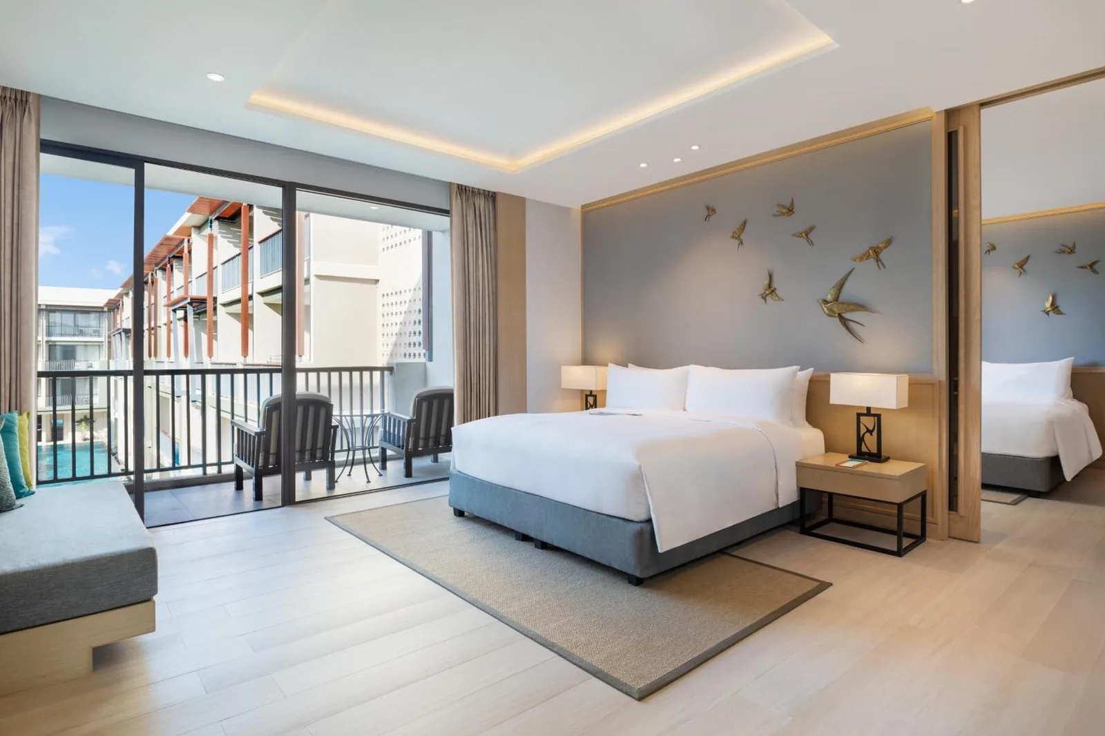 Bright modern guest room at Le Meridien Khao Lak Resort & Spa with king bed, balcony, and contemporary decor.